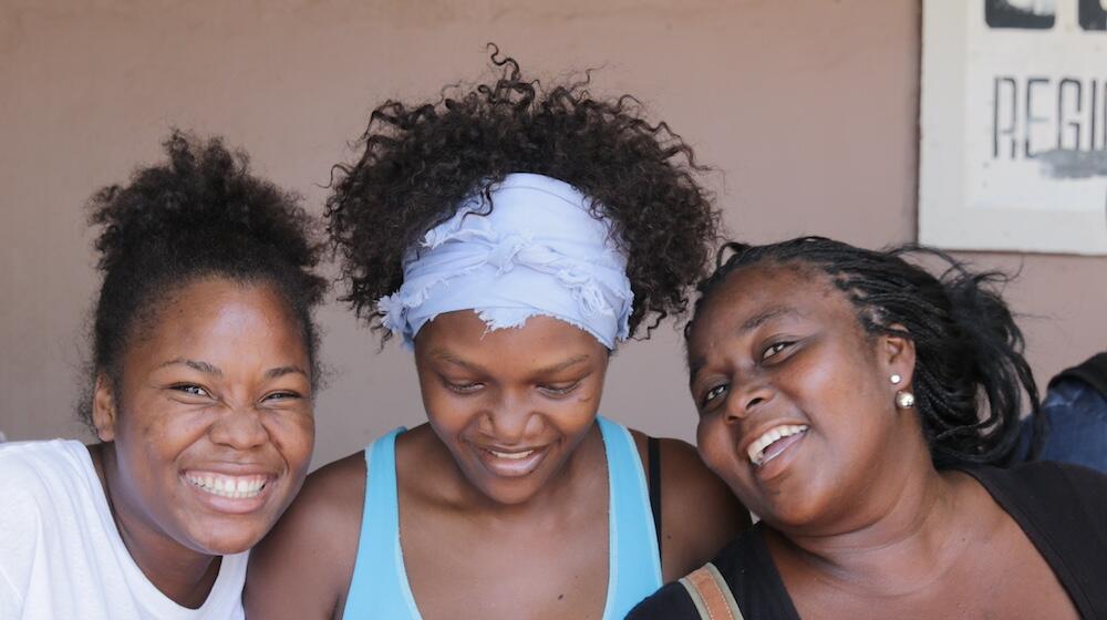 ثلاث نساء منحدرات من أصل إفريقي يبتسمن.